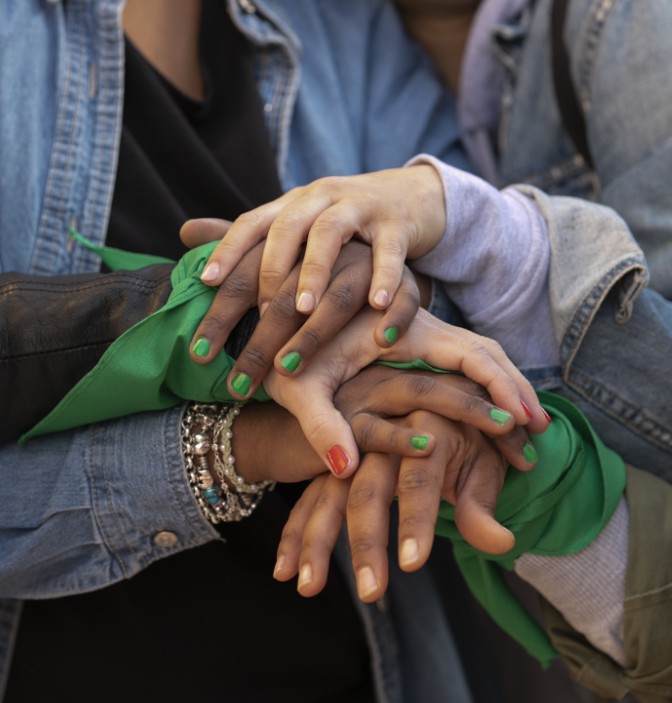Manos entrelazadas de mujeres con pañuelos verdes y uñas pintadas de colores, simbolizando la sororidad, la diversidad y la solidaridad promovidas por la FUNDACIÓN ARTÍSTICA DEPORTIVA Y CULTURAL FUNCULTURA 369.
